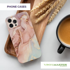Puede incluir: Una funda para tel&eacute;fono con un dise&ntilde;o de m&aacute;rmol rosa, azul y dorado. La funda est&aacute; sobre una superficie de madera. El texto "PHONE CASES" est&aacute; en la parte superior de la imagen.