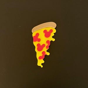 May include: A slice of pizza with a yellow base, red toppings, and a tan crust. The red toppings are shaped like Mickey Mouse heads. The pizza slice is on a black background.