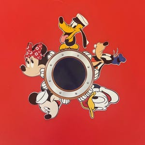 May include: A red background featuring Disney characters Minnie Mouse, Mickey Mouse, Pluto, and Donald Duck surrounding a circular porthole. Minnie wears a red bow, Pluto a sailor hat. The porthole has a silver frame and a dark center.