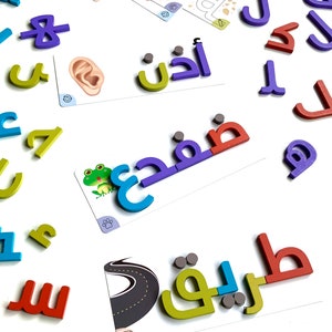 May include: Colorful magnetic letters in Arabic script, including the words "أنا" (I), "فهم" (understand), and "طريق" (road). The letters are arranged on a white surface with other letters and cards.