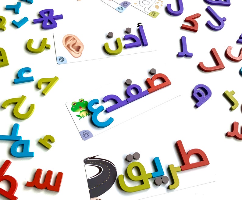 May include: Colorful magnetic letters in Arabic script, including the words "أنا" (I), "فهم" (understand), and "طريق" (road). The letters are arranged on a white surface with other letters and cards.