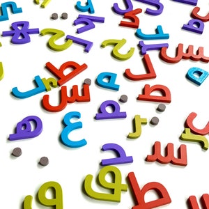 May include: A collection of colorful wooden letters in various shapes and sizes. The letters are scattered on a white surface. The letters are in different colors, including red, blue, yellow, purple, and green.