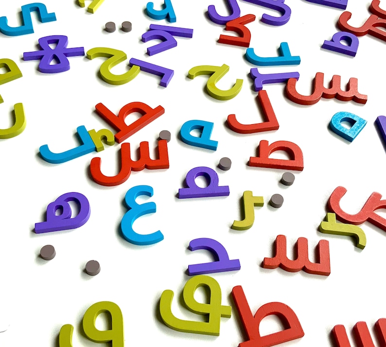 May include: A collection of colorful wooden letters in various shapes and sizes. The letters are scattered on a white surface. The letters are in different colors, including red, blue, yellow, purple, and green.