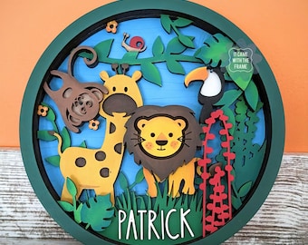May include: A green circular wooden plaque with a layered design featuring a giraffe, lion, monkey, and toucan in a jungle setting. The plaque has the name "Patrick" written in white letters at the bottom.