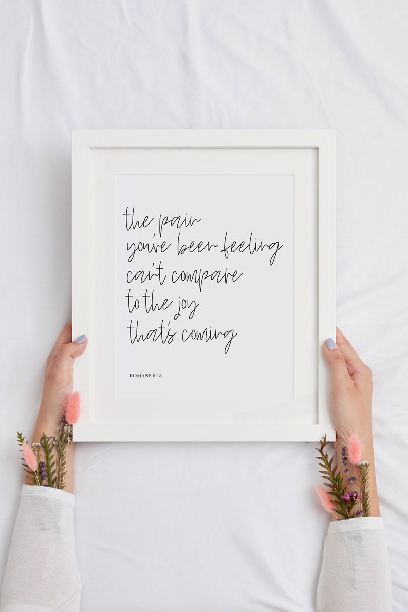 May include: White framed print with the text "the pain you've been feeling can't compare to the joy that's coming" and the scripture reference "ROMANS 8:18".
