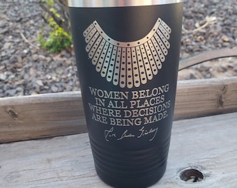 May include: Black stainless steel tumbler with a gold design of a judge's collar and the quote "Women belong in all places where decisions are being made."  The quote is attributed to Ruth Bader Ginsburg.