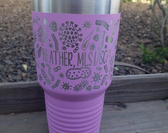 May include: A pink stainless steel tumbler with a silver lid. The tumbler has a design of various bacteria and the text "HEATHER, MLS (ASCP)" on the side.
