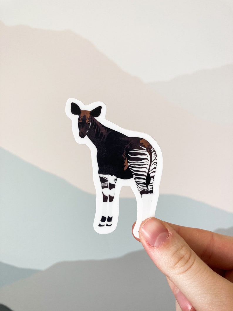 May include: A sticker featuring a black and white okapi, a mammal native to the Democratic Republic of the Congo, with a brown head and legs.