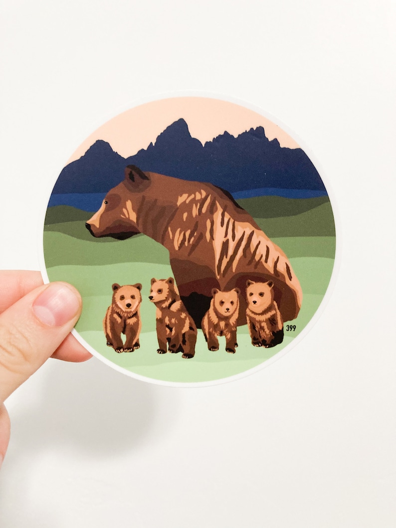 May include: A brown bear with four cubs in a mountain landscape. The bear and cubs are standing on a green field with a blue lake and mountains in the background. The sky is a light orange color.