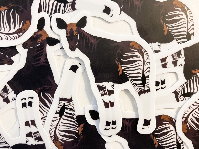 May include: A set of stickers featuring black and white striped okapi illustrations. The okapi is a mammal native to the Democratic Republic of the Congo.
