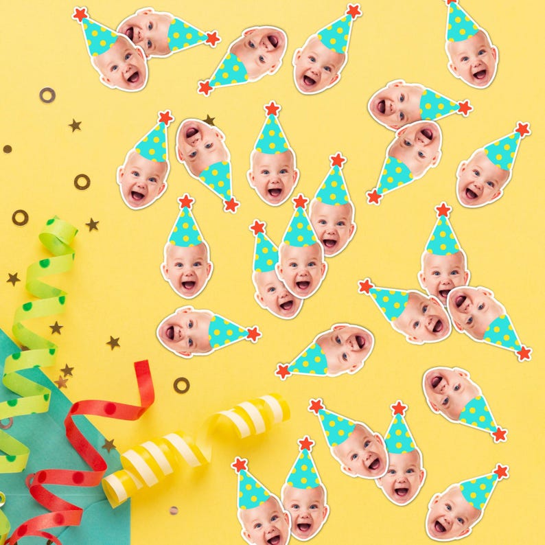 May include: A collection of paper confetti pieces featuring a repeating photographic print of a baby wearing a bright turquoise party hat with yellow polka dots and a red star topper, scattered across a solid yellow surface with streamers.
