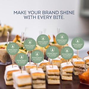 May include: An assortment of appetizers with small, round, light green Pinecrest Academy logo toppers on wooden skewers. The text "MAKE YOUR BRAND SHINE WITH EVERY BITE" is at the top of the image.