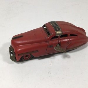 May include: Red wind-up toy car with a key on the side and "Auto-Tex" written on the top.
