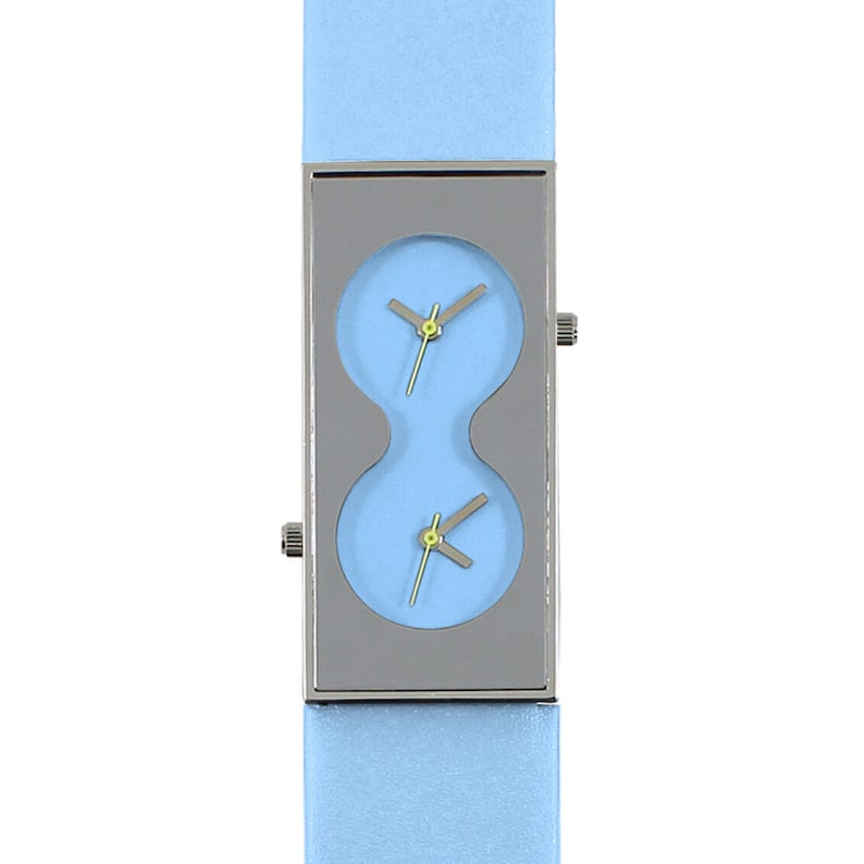 May include: A light blue wristwatch with a silver rectangular case and two round watch faces. The watch has a light blue leather band.