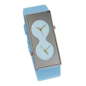 May include: A light blue wristwatch with a silver rectangular case and two round watch faces. The watch has a light blue band.