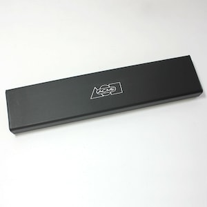 May include: A black rectangular box with the word "ACME" printed in white on the top. The box is made of a smooth, hard material.
