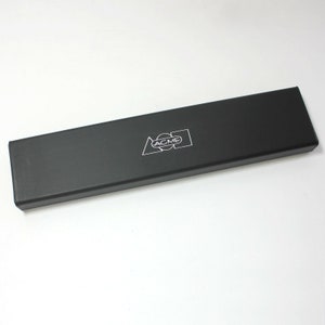 May include: A black rectangular box with the word "ACME" printed in white on the top. The box is made of a smooth, hard material.
