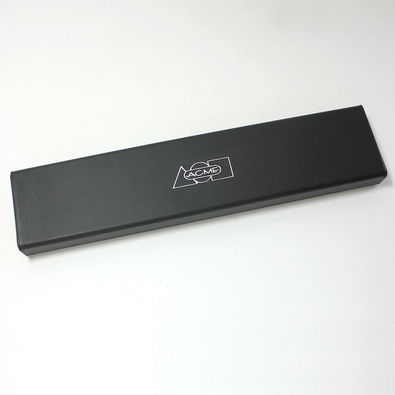 May include: A black rectangular box with the word "ACME" printed in white on the top. The box is made of a smooth, hard material.