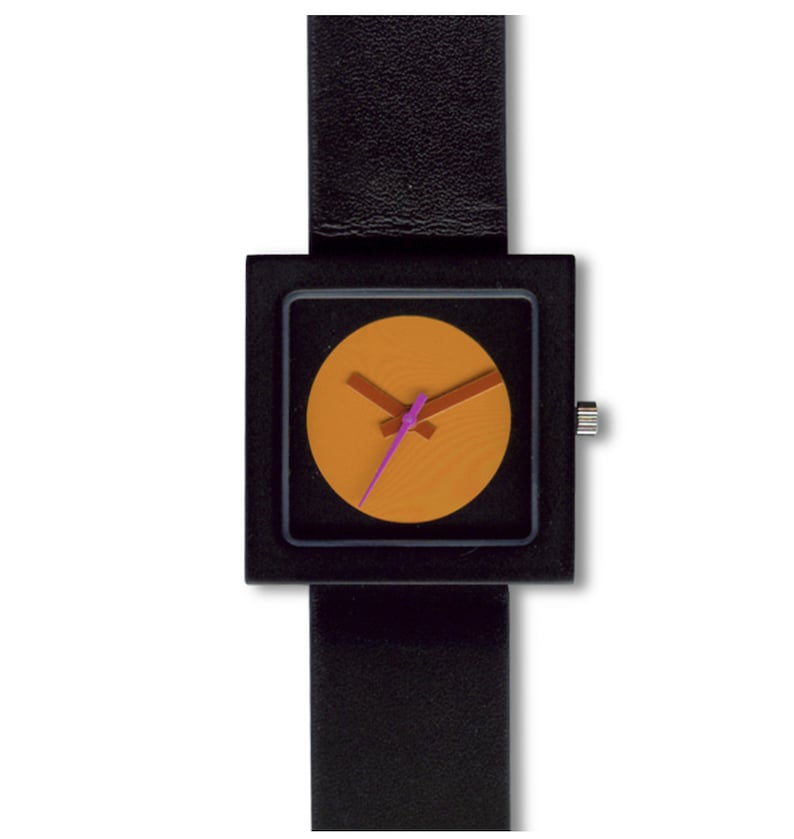 K&ouml;nnte beinhalten: Eine schwarze quadratische Uhr mit einem schwarzen Lederarmband. Das Zifferblatt der Uhr ist ein Kreis mit orangefarbenem Hintergrund und rosa und braunen Zeigern.