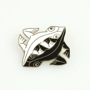 May include: A black and white enamel pin featuring a stylized design of two fish intertwined. The fish are facing opposite directions, with one fish being white and the other black.