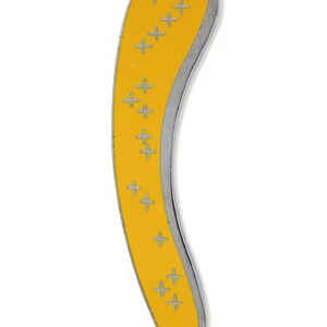 May include: A yellow metal pin in the shape of a curved rectangle with a silver border. The pin has a pattern of small silver plus signs on the yellow surface.