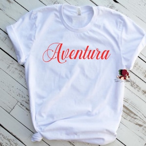 May include: White t-shirt with the word "Aventura" printed in red cursive lettering.