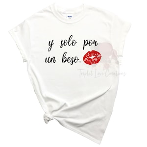 May include: White t-shirt with black text that reads "y solo por un beso..." and a red lipstick print.