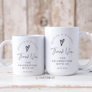 May include: Two white ceramic mugs with black text and a heart design. The text on the mugs reads "Olivia & Daniel" and "Thank You for Celebrating with Us 08.31.2024".