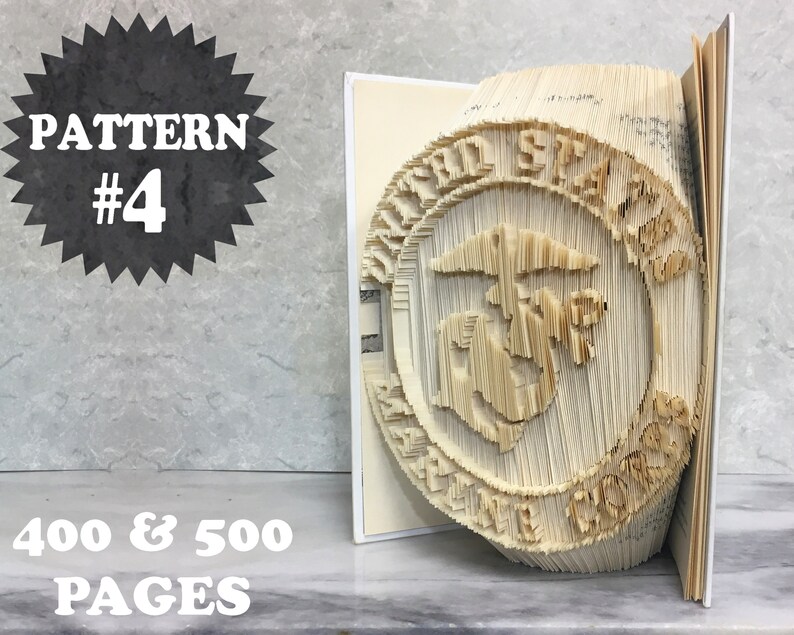 May include: A book art sculpture of the United States Marine Corps emblem. The sculpture is made from the pages of a book that has been folded and cut to create a three-dimensional design. The sculpture is on a shelf with the text "PATTERN #4 400 & 500 PAGES" visible.