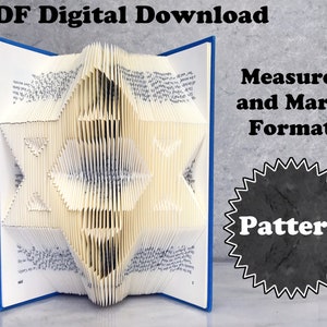 Könnte beinhalten: Ein blaues Buch mit einem darin gefalteten weißen Papierstern. Das Buch ist geöffnet und der Stern steht aufrecht. Der Text "PDF Digitaler Download" befindet sich oben im Bild. Der Text "Mess- und Markierungsformat" befindet sich rechts im Bild. Ein schwarzer Stern mit dem Text "Muster" befindet sich in der unteren rechten Ecke des Bildes.