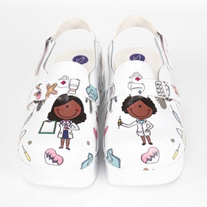 May include: White slip-on clogs with a cartoon doctor design. The clogs feature a black and white cartoon doctor with a stethoscope and a red cross. The clogs also feature other medical symbols, such as a heart, a bandage, and a syringe.
