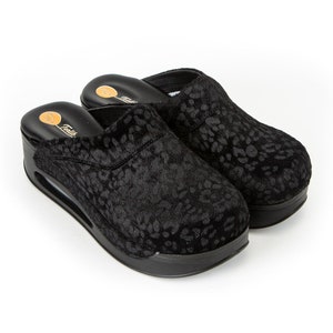May include: A pair of black leopard print slippers with a thick platform sole.