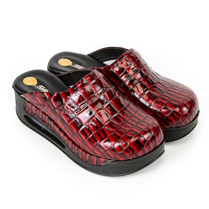 Könnte beinhalten: Ein Paar rote Lederslipper mit Krokodilmuster. Die Slipper haben eine schwarze Plateau-Sohle und eine geschlossene Spitze.