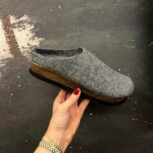 Può includere: Ciabatte in feltro grigio con suola platform dorata e nera.