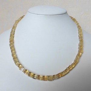 May include: A gold necklace made of faceted, square-shaped citrine beads.