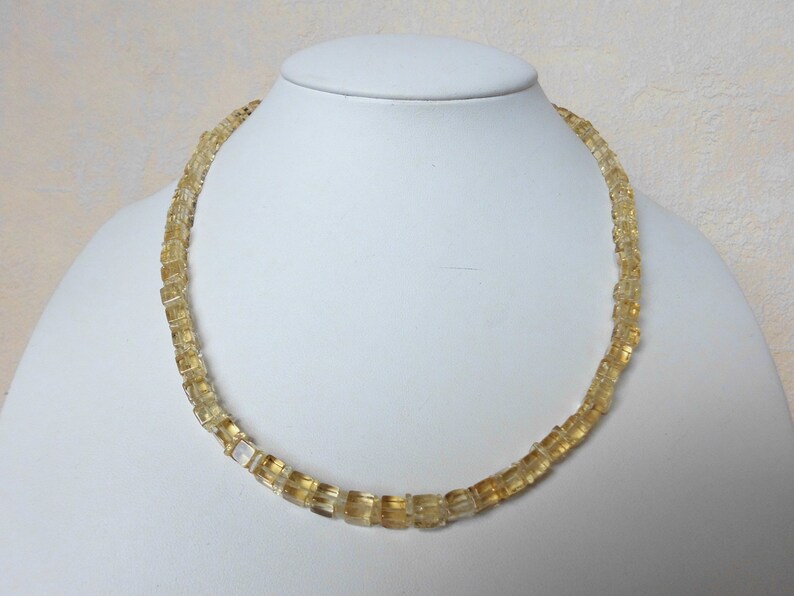 May include: A gold necklace made of faceted, square-shaped citrine beads.