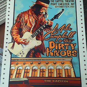 May include: A concert poster for Mike Campbell & The Dirty Knobs, featuring a colorful illustration of Mike Campbell playing a guitar. The poster advertises a show at The Capitol Theatre in Port Chester, NY on September 16th, 2022.