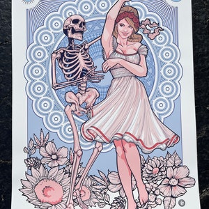 May include: Art print featuring a dancing skeleton and a woman in a white dress, set against a blue and white decorative background. Floral elements and the text "St. Louis 2023 June 7th" are at the bottom.