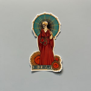 May include: A sticker featuring a skeleton figure in a red kimono holding a traditional Japanese umbrella. The figure is surrounded by sunflowers and the text "CHIKA CAT SUNFLOWER" is at the bottom.