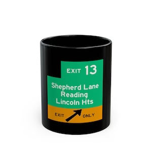 May include: Black ceramic mug with a green and yellow graphic. The graphic reads "EXIT 13" above "Shepherd Lane Reading Lincoln Hts" and "EXIT ONLY" with an arrow. A novelty item.