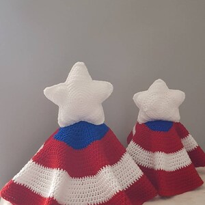 May include: Two crocheted star-shaped pillows with red, white, and blue striped blankets. The star pillows are white, and the blankets have a patriotic design. The items are handmade and suitable for home decor.