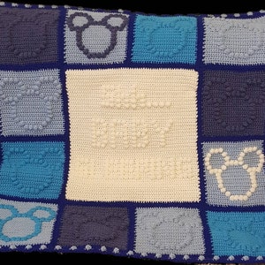 May include: A blue and white crocheted baby blanket with a Mickey Mouse design. The blanket is made up of squares with different patterns, including a solid white square in the center.