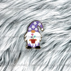 May include: A purple gnome with a white beard and a white hat with purple flowers. The gnome is holding a red pot with a green plant and purple flowers.