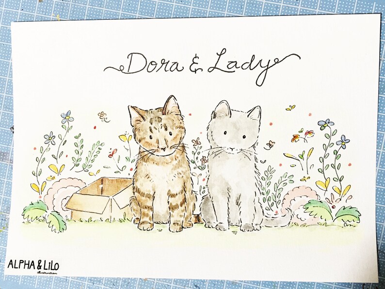 May include: A watercolor painting of two cats named Dora and Lady. The cats are sitting in a field of flowers. The cat on the left is brown and tabby, and the cat on the right is gray. There is a cardboard box in the background.
