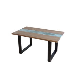 Peut inclure: Une table en bois avec une rivière de résine bleu clair traversant le centre. La table a des pieds en métal noir.
