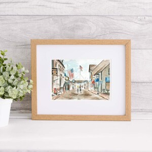 Puede incluir: Una pintura de acuarela de una escena callejera con edificios, banderas y personas caminando. Los edificios est&aacute;n pintados en tonos de gris y marr&oacute;n, y las banderas son rojas, blancas y azules. Las personas est&aacute;n pintadas en tonos de azul y marr&oacute;n.