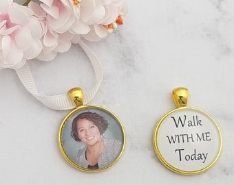May include: Two gold-colored round charms with white ribbon. One charm has a photo of a woman with brown hair and a black and white striped shirt. The other charm has the text "Walk with me today".