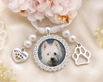 May include: A silver-toned circular pendant featuring a photograph of a white dog, surrounded by a border of clear crystals. The pendant hangs from a white ribbon with two pearl-accented charms: a heart inscribed with BEST FRIEND and a paw print.