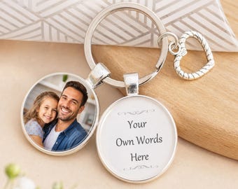 May include: A silver-toned metal keychain featuring two circular charms attached to a split ring and a small heart-shaped charm. One charm displays a color photograph of a man and a young girl smiling, while the other charm features the text Your Own Words Here.