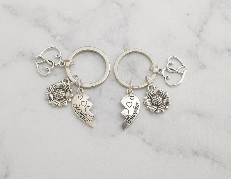 May include: Two silver keychains with a sunflower charm, a heart charm, and a split heart charm that says "Mother" and "Daughter".